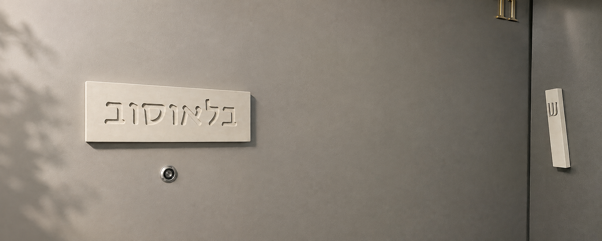 שלט כניסה לבית מבטון עם שם משפחה על דלת הכניסה